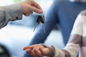 Car dealer giving keys to a customer in a car shop